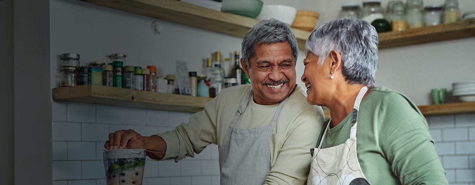 Happy senior couple cooking healthy food in their kitchen.