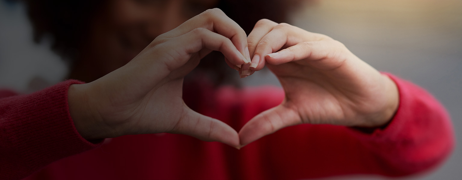 woman holding her hands in the shape of a heart