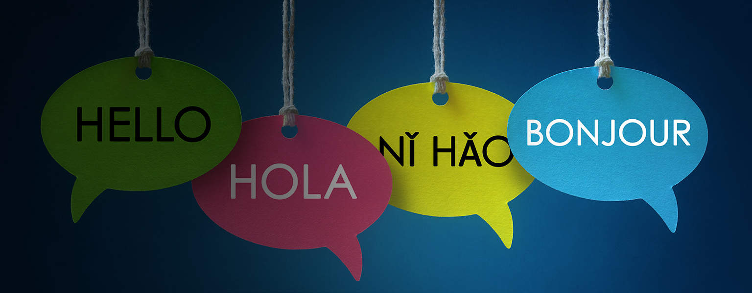 Foreign language colorful communication speech bubbles hanging from a cord over blue background